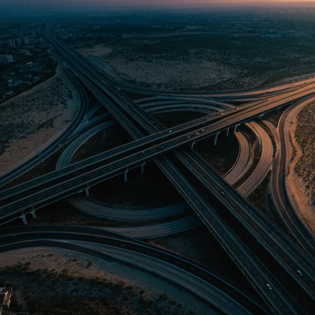 High aerial view of a Dubai interchange at dusk with curving ramps laid out in nested bands