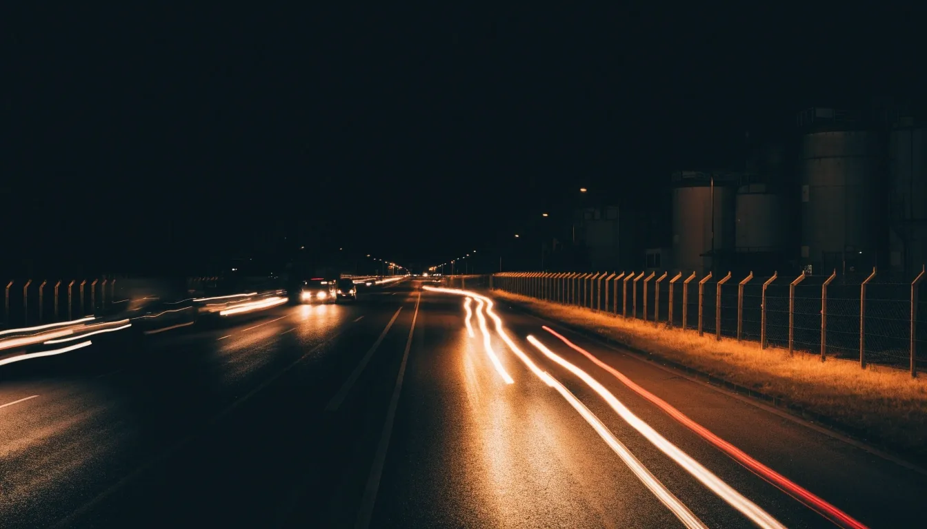 Night freight corridor under warm street light with light trails from trucks on the carriageway