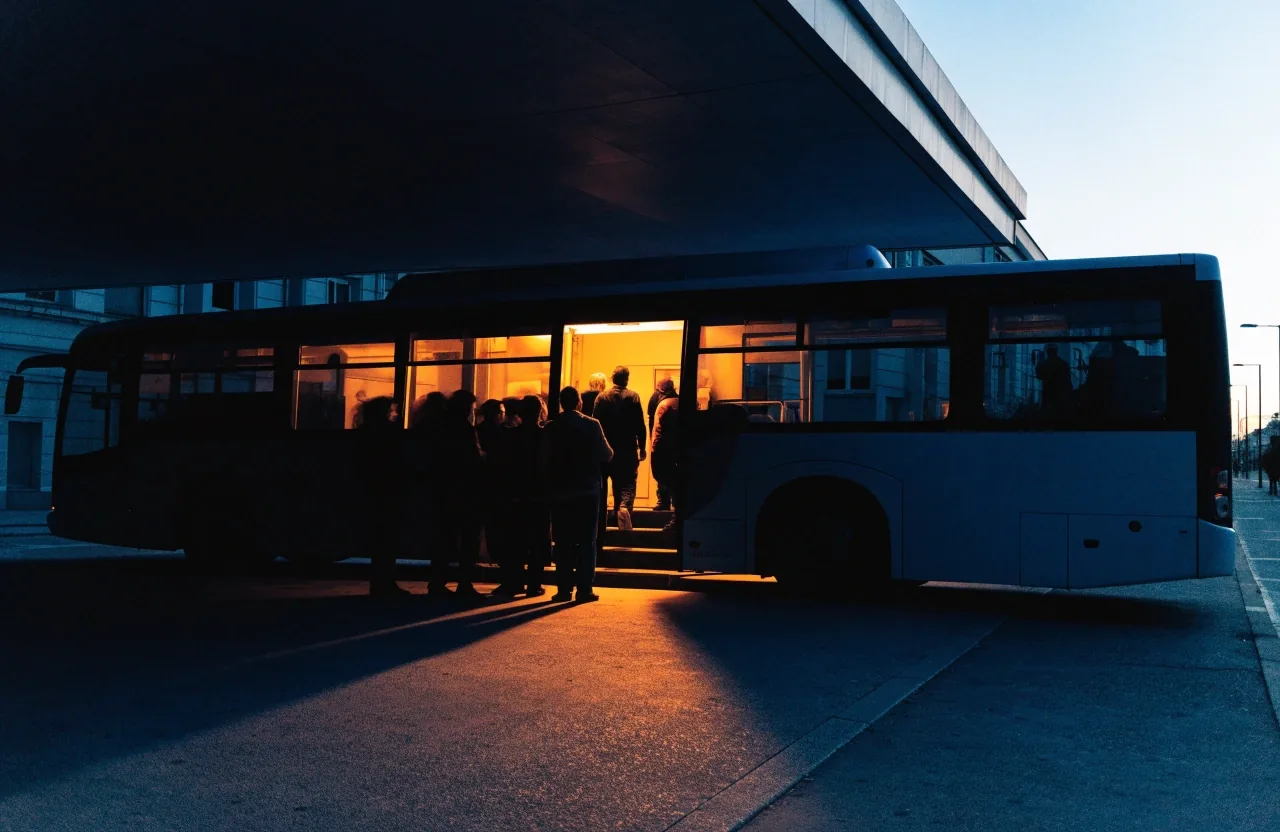 Metro platform edge at last light with commuters in silhouette