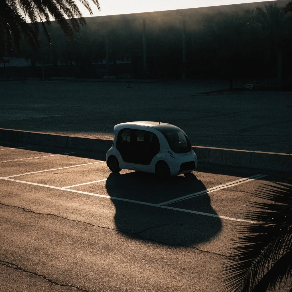 Driverless shuttle resting in its bay on a Gulf campus at low sun