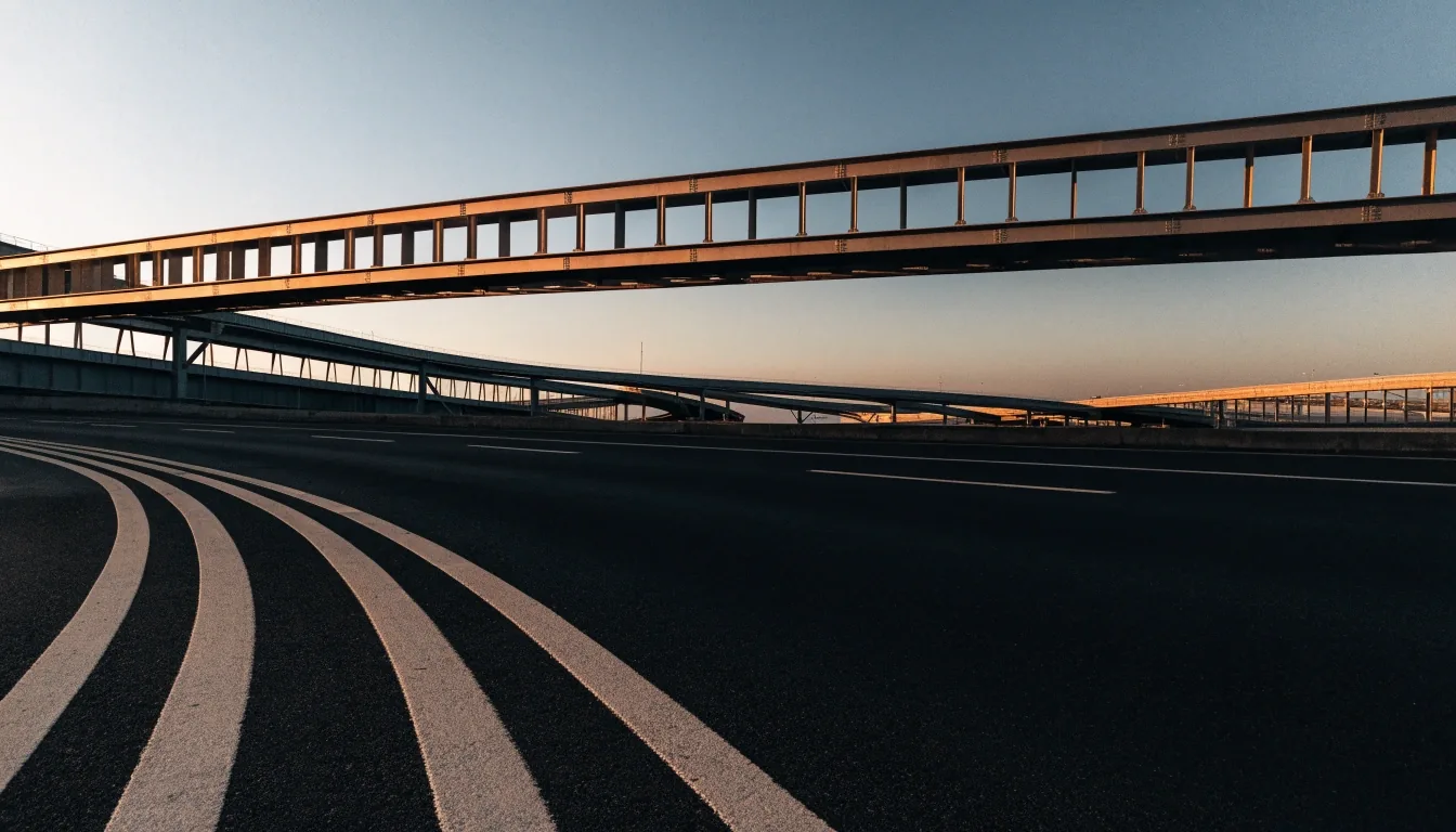 A Gulf coastal road at dusk seen from an overpass, with warm horizon light and deep shadow across the carriageway