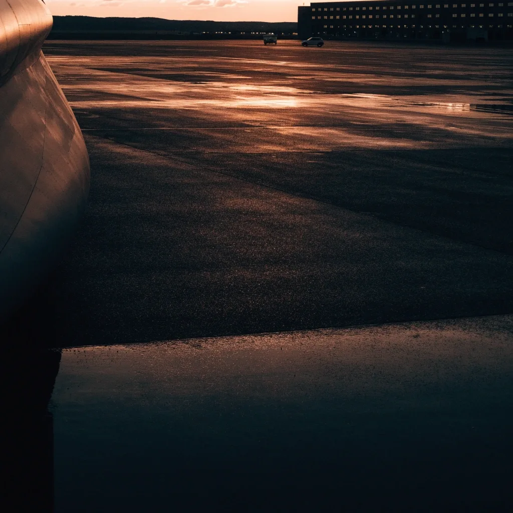 Airport apron and terminal edge at dusk with an unmarked aircraft visible in low light