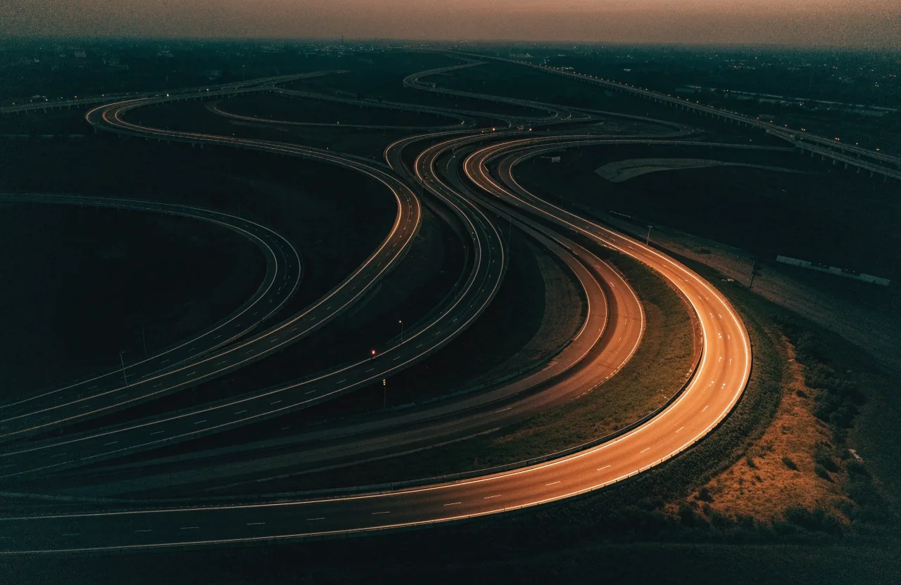 Aerial view of a Gulf highway interchange at dusk with layered curving ramps